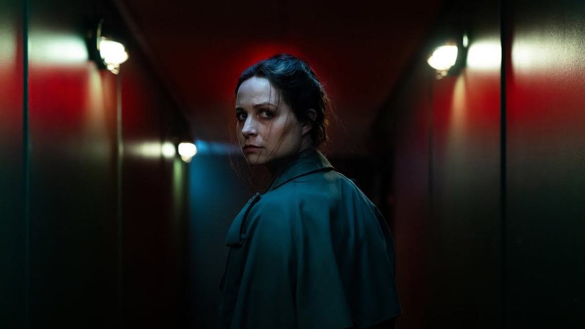 Still from Censor, a woman looks over here shoulder