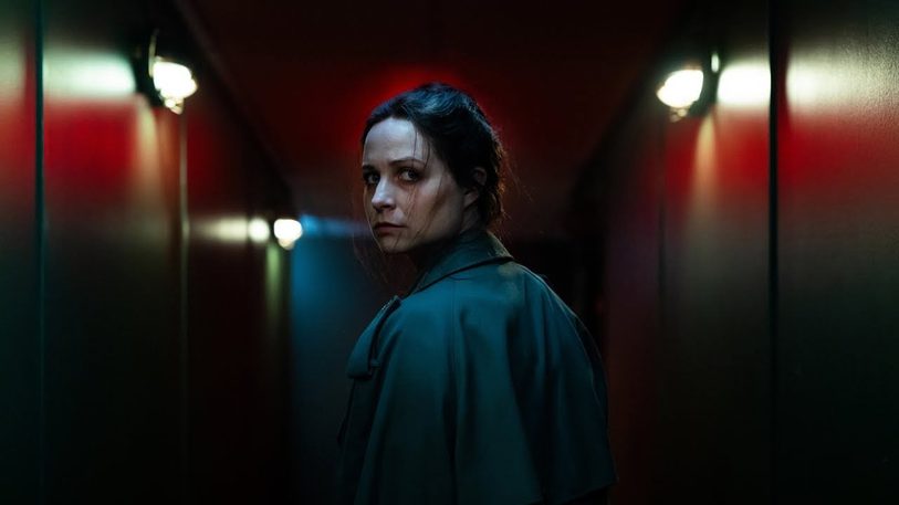 Still from Censor, a woman looks over here shoulder