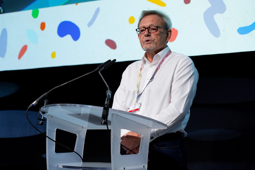 Julian Scott standing at lectern speaking at Cartoon Forum