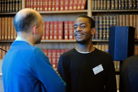 Nimai Inniss infront of bookcase smiling