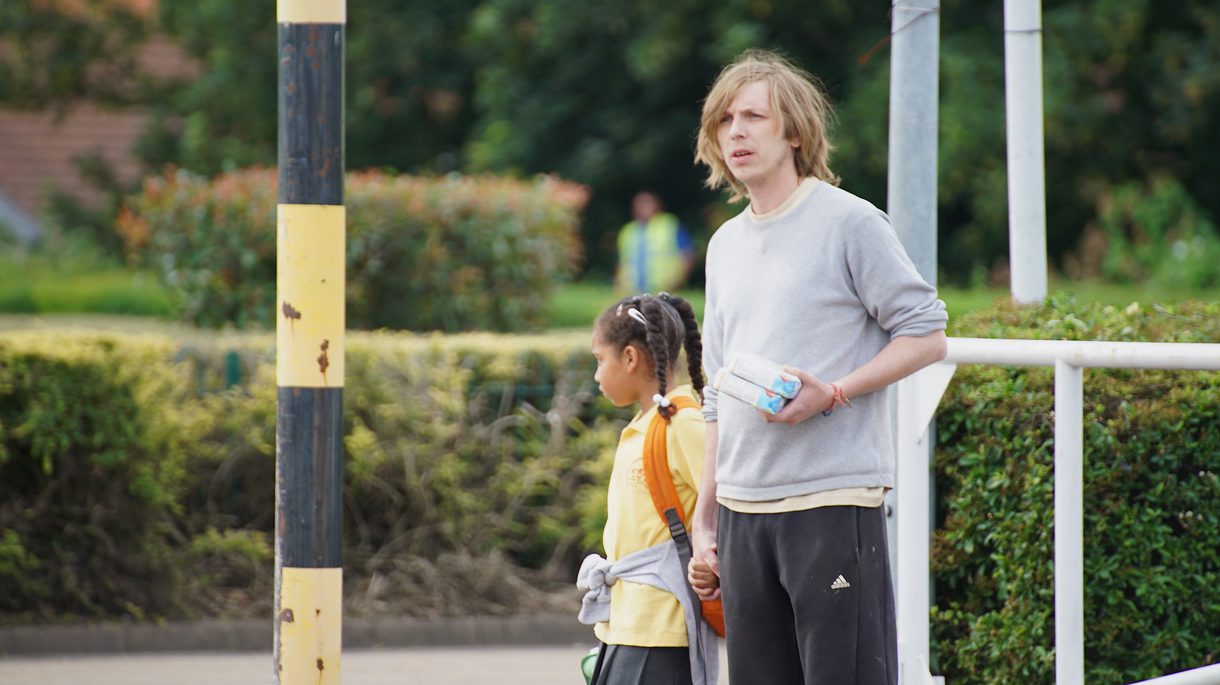 A young man holds the hand of a young girl at a traffic crossing