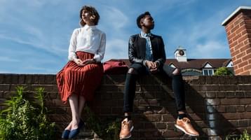 Still of short film Baby Gravy. Two young women sit on top of a wall