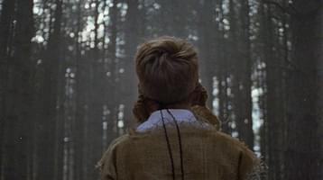 Still of Wren Boys. Back of a mans head in the woods