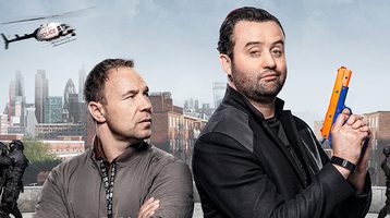 Promotional image of Code 404. Medium shot of two men, one looking at the other.