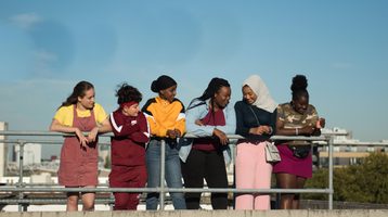 Still from Rocks featuring six young women looking over a railing.