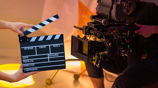 Person operating a camera behind a clapperboard on set